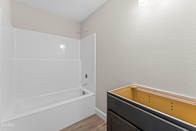 bathroom featuring wood finished floors and washtub / shower combination