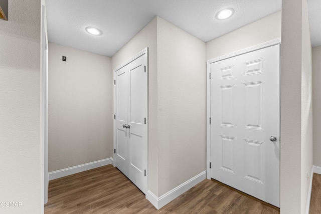 hall featuring wood finished floors, baseboards, and recessed lighting
