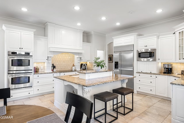 kitchen featuring built in appliances, white cabinets, light stone countertops, and tasteful backsplash