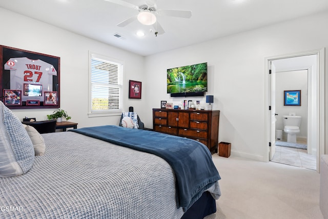 bedroom featuring ceiling fan, ensuite bathroom, and light colored carpet