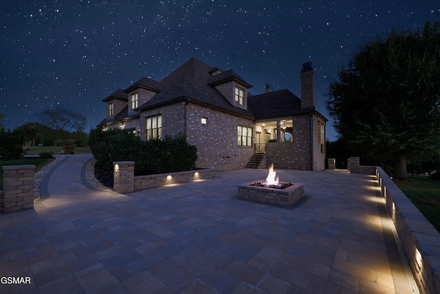 property exterior at twilight featuring a patio and a fire pit