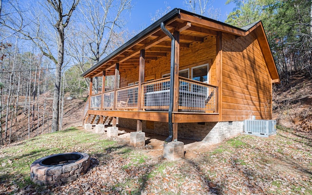 view of home's exterior with a fire pit, a wooden deck, and central air condition unit