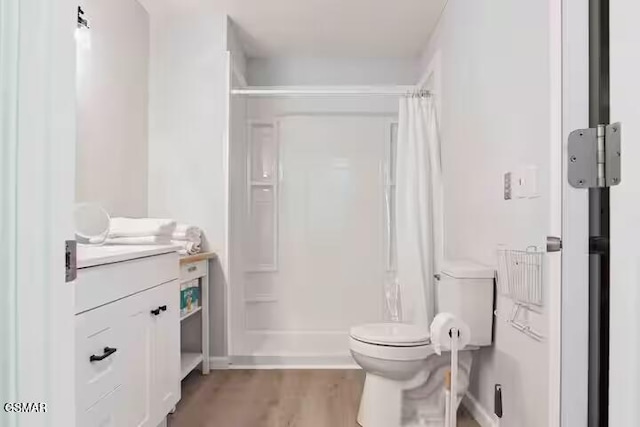 bathroom with vanity, toilet, hardwood / wood-style floors, and walk in shower