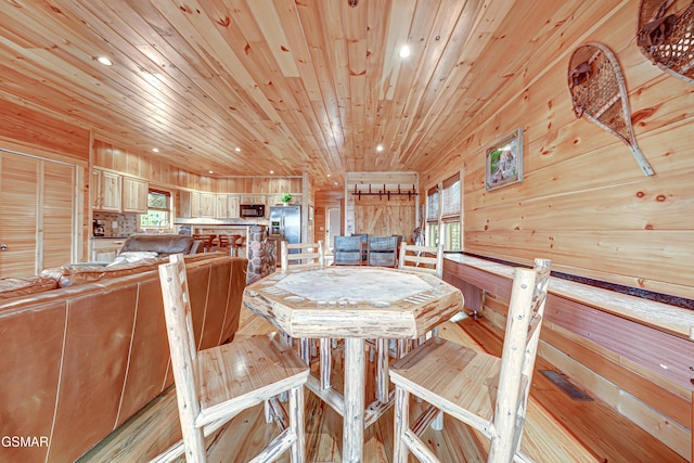 dining space featuring wood walls, wood ceiling, and light wood-type flooring