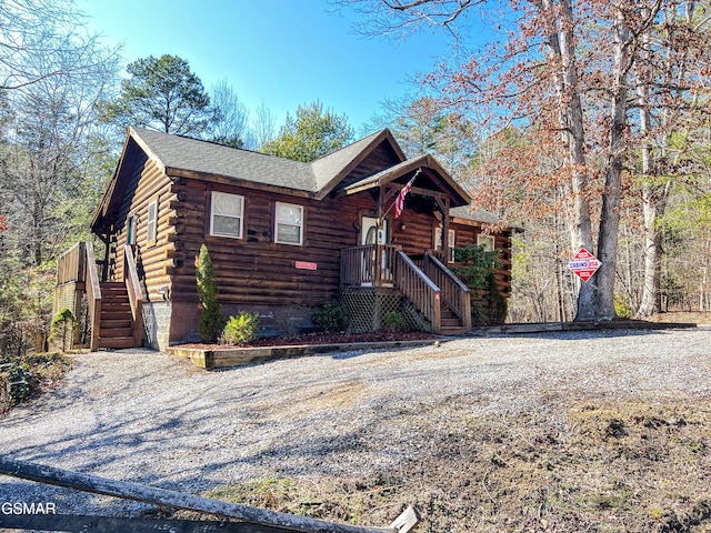 log home with stairway, log exterior, and roof with shingles