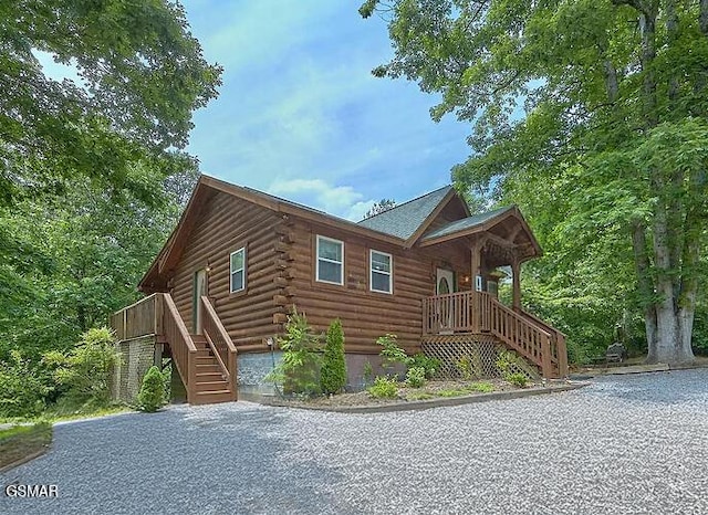 cabin featuring stairs and log siding