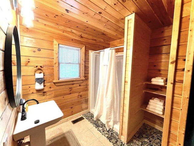 bathroom featuring a shower with shower curtain, wood walls, wooden ceiling, and sink