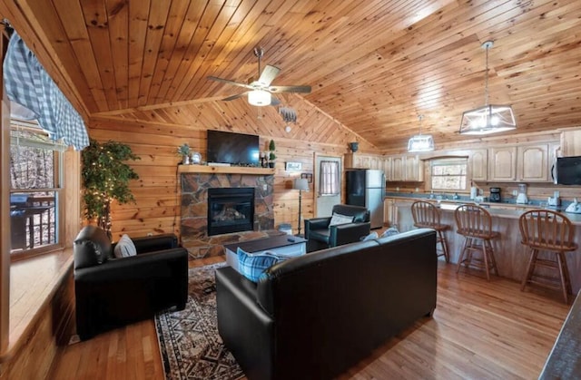 living room featuring light wood-type flooring, wooden walls, ceiling fan, and lofted ceiling