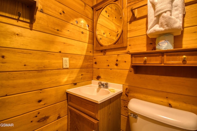 bathroom featuring wooden walls, toilet, and vanity