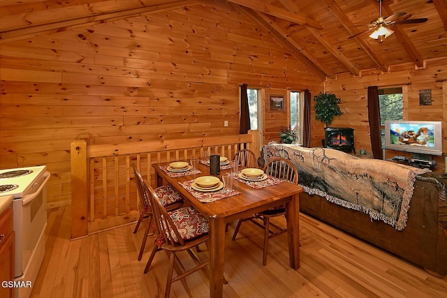 dining space featuring wooden ceiling, lofted ceiling with beams, a ceiling fan, wooden walls, and light wood-style flooring