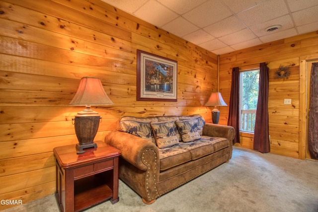 living room featuring wood walls, visible vents, a paneled ceiling, and carpet floors