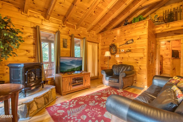 living area with wood walls, a wood stove, wooden ceiling, and lofted ceiling with beams