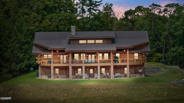 back house at dusk with a deck and a yard