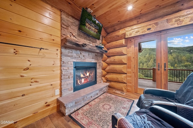 living room with french doors, rustic walls, wood-type flooring, wooden ceiling, and a stone fireplace