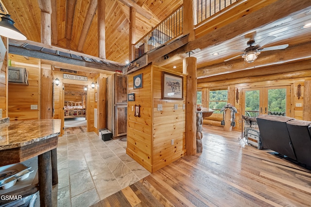 hallway featuring french doors, wooden walls, log walls, high vaulted ceiling, and wooden ceiling