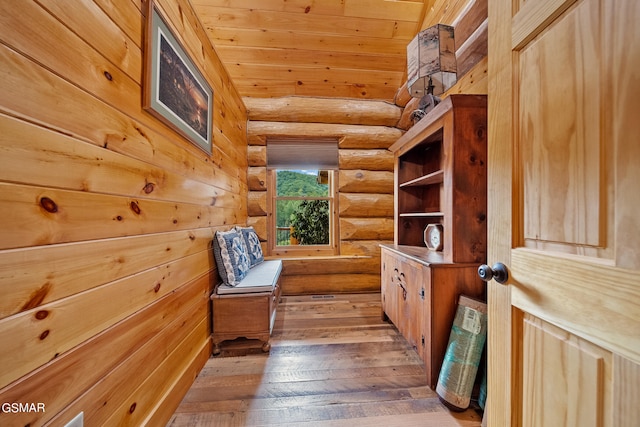 sitting room with hardwood / wood-style floors, wooden ceiling, log walls, and vaulted ceiling