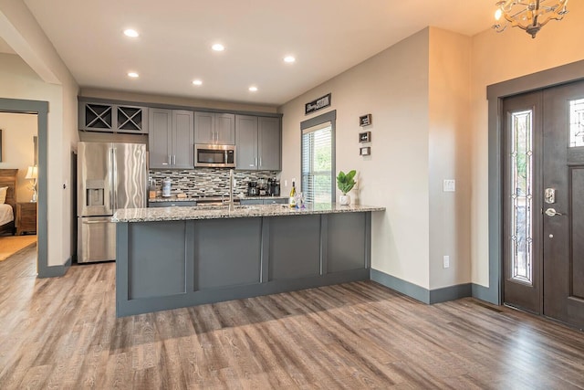 907 Village Loop Rd, Gatlinburg, TN 37738 - kitchen featuring light stone countertops, stainless steel appliances, tasteful backsplash, light hardwood / wood-style floors, and gray cabinets