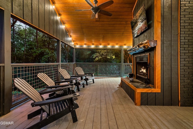 wooden terrace featuring exterior fireplace and ceiling fan