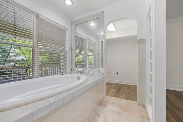 bathroom with crown molding and tiled bath