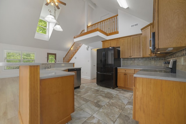 kitchen featuring a skylight, ceiling fan, sink, decorative backsplash, and appliances with stainless steel finishes