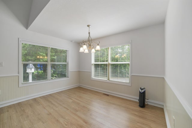 unfurnished dining area with light hardwood / wood-style floors and an inviting chandelier