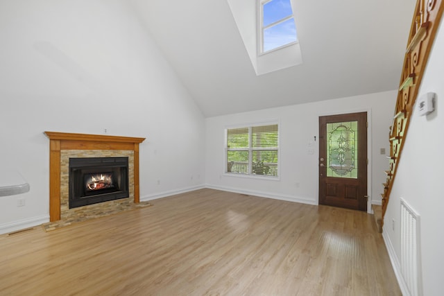 unfurnished living room with light wood-type flooring, high vaulted ceiling, and a skylight