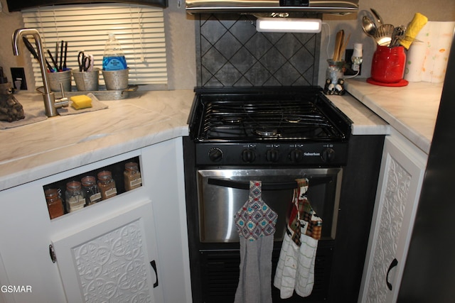 kitchen featuring light countertops, tasteful backsplash, and black range with gas stovetop