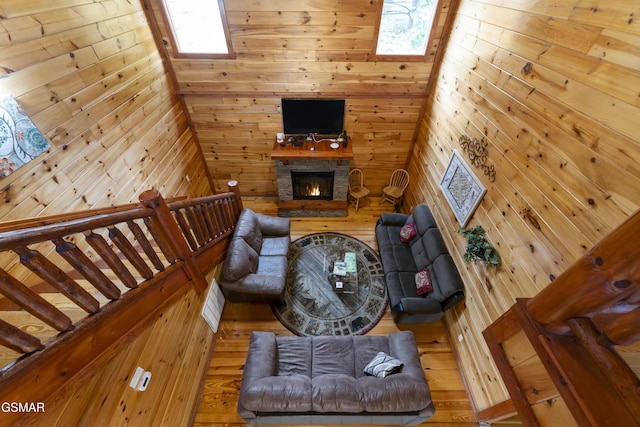 living room with hardwood / wood-style flooring, wood walls, and a fireplace