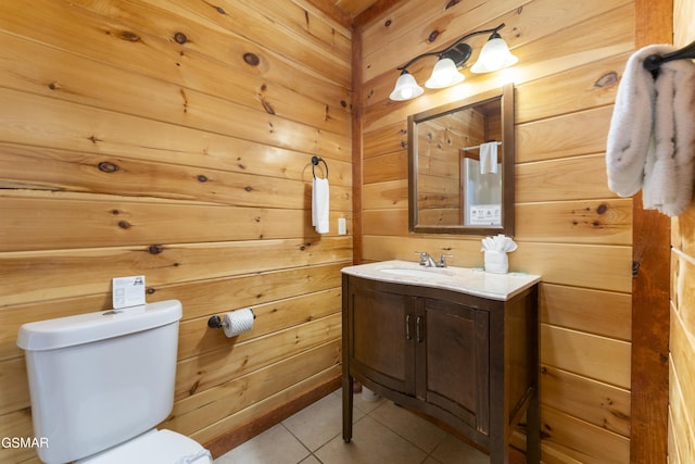 bathroom featuring tile patterned flooring, vanity, toilet, and wood walls