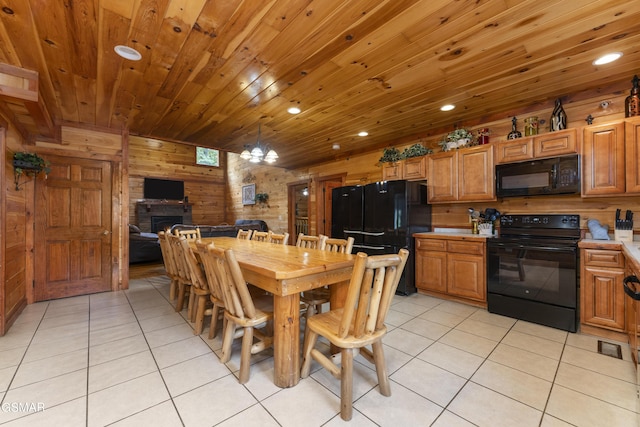 tiled dining area featuring an inviting chandelier, a stone fireplace, and wood walls