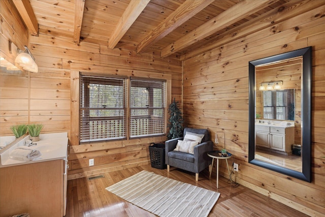 sitting room featuring wooden walls, beamed ceiling, wood ceiling, and light hardwood / wood-style floors