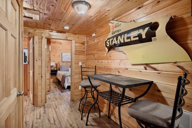 dining space featuring wooden ceiling, wooden walls, and light hardwood / wood-style flooring