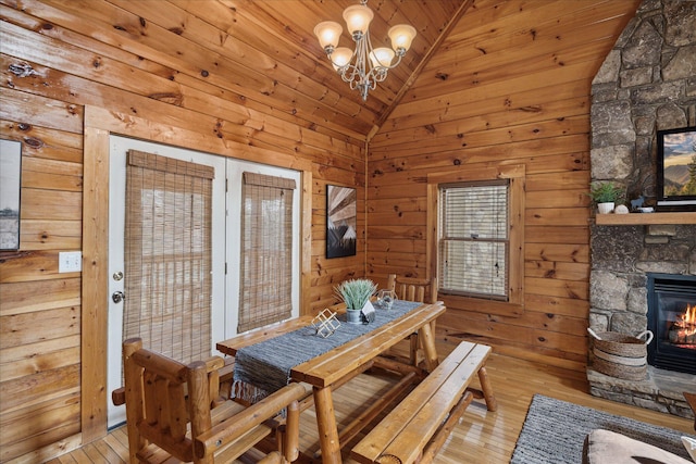 dining space with wooden walls, a fireplace, a chandelier, and light wood-type flooring