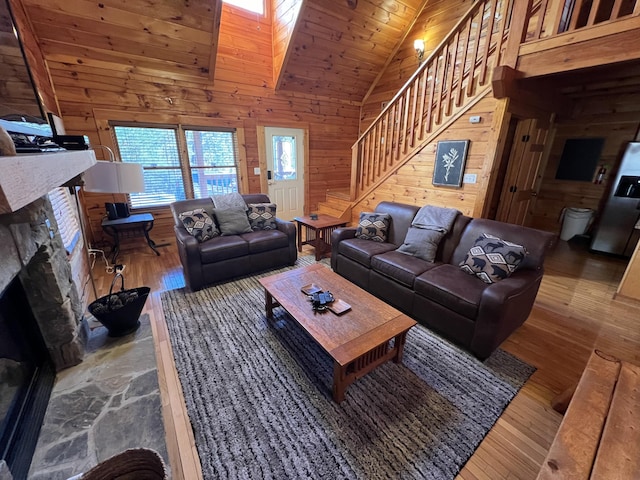 living room featuring wooden ceiling, a stone fireplace, high vaulted ceiling, wooden walls, and hardwood / wood-style flooring