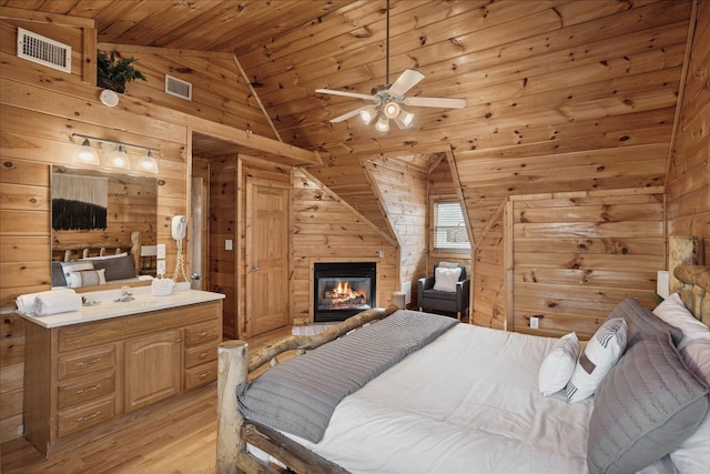 bedroom featuring wood walls, vaulted ceiling, light hardwood / wood-style flooring, ceiling fan, and wood ceiling