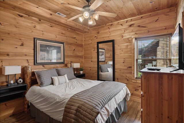 bedroom featuring wooden walls, hardwood / wood-style flooring, ceiling fan, and wooden ceiling