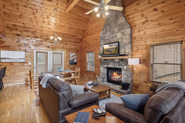 living room featuring wooden walls, a fireplace, high vaulted ceiling, and light hardwood / wood-style floors