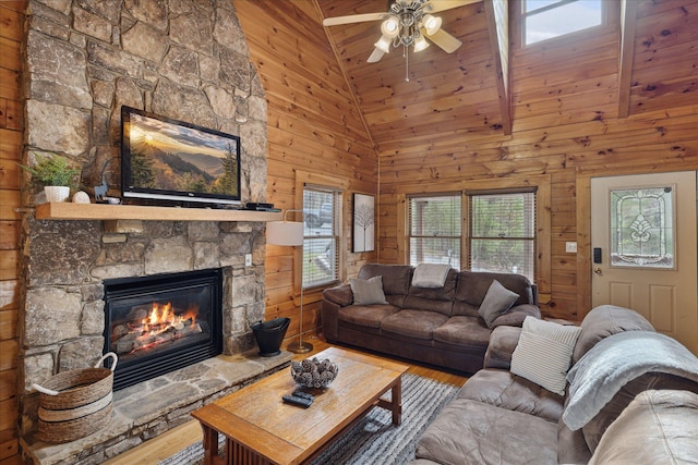 living room featuring a stone fireplace, wood ceiling, and wooden walls