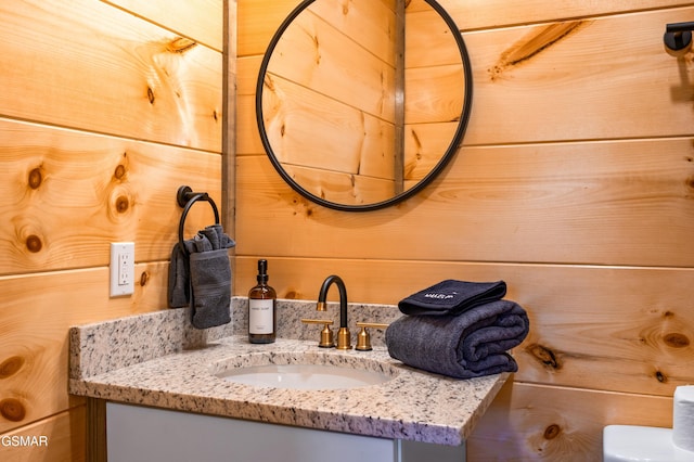 half bath featuring wood walls and vanity