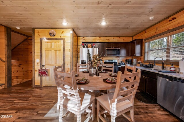 dining room with dark wood-type flooring, wooden ceiling, recessed lighting, and wooden walls