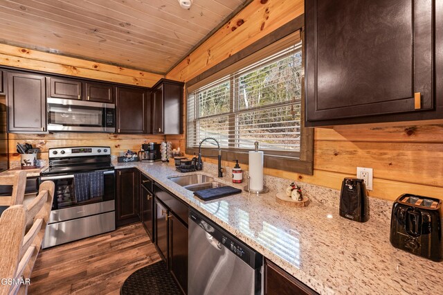 kitchen featuring appliances with stainless steel finishes, wood ceiling, a sink, wood walls, and dark brown cabinetry