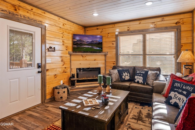 living area with wood ceiling, wood walls, a lit fireplace, and wood finished floors