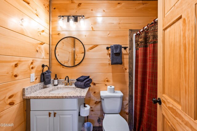 bathroom with toilet, wooden walls, a shower with shower curtain, and vanity