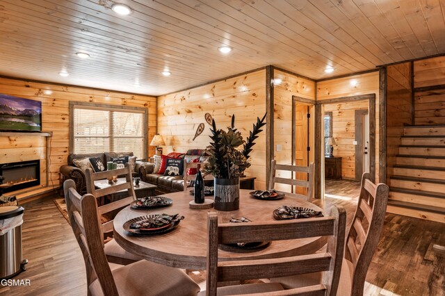 dining room featuring a glass covered fireplace, wood ceiling, wood finished floors, wood walls, and recessed lighting