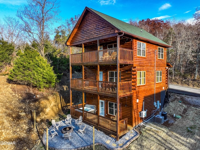 rear view of house with a balcony, a patio area, a fire pit, and cooling unit