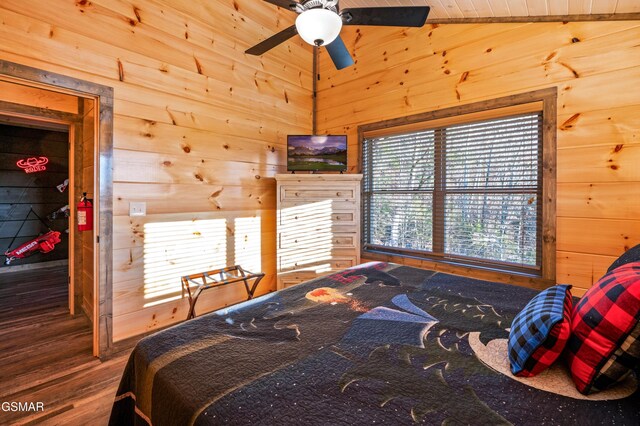 bedroom featuring vaulted ceiling, wood finished floors, and wooden walls