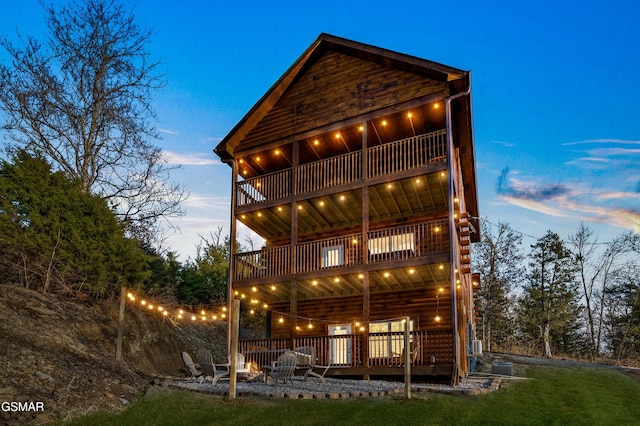 back of house featuring a fire pit, a balcony, and faux log siding