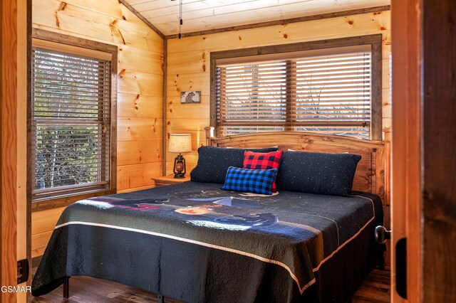 bedroom featuring lofted ceiling, wood walls, and wood finished floors