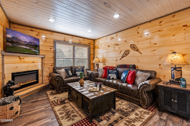 living area featuring a glass covered fireplace, wooden ceiling, wood walls, and wood finished floors