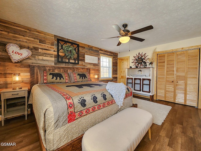 bedroom with a closet, wooden walls, wood finished floors, and a textured ceiling